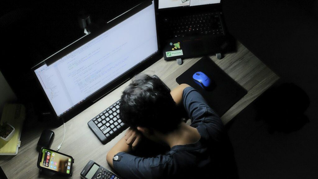 Tired person resting at a desk late at night, a sign to stay out of the market