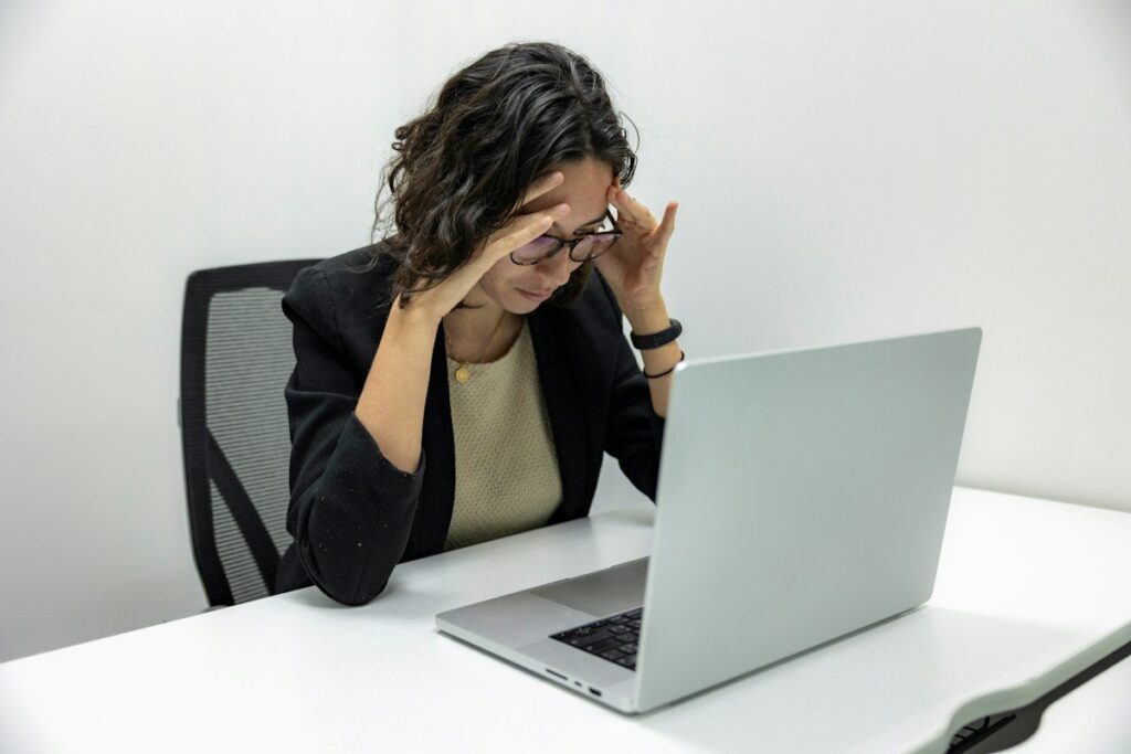 Tired person rubbing their eyes at a computer