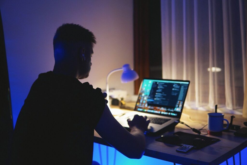 Person working at a laptop at a home desk in the evening