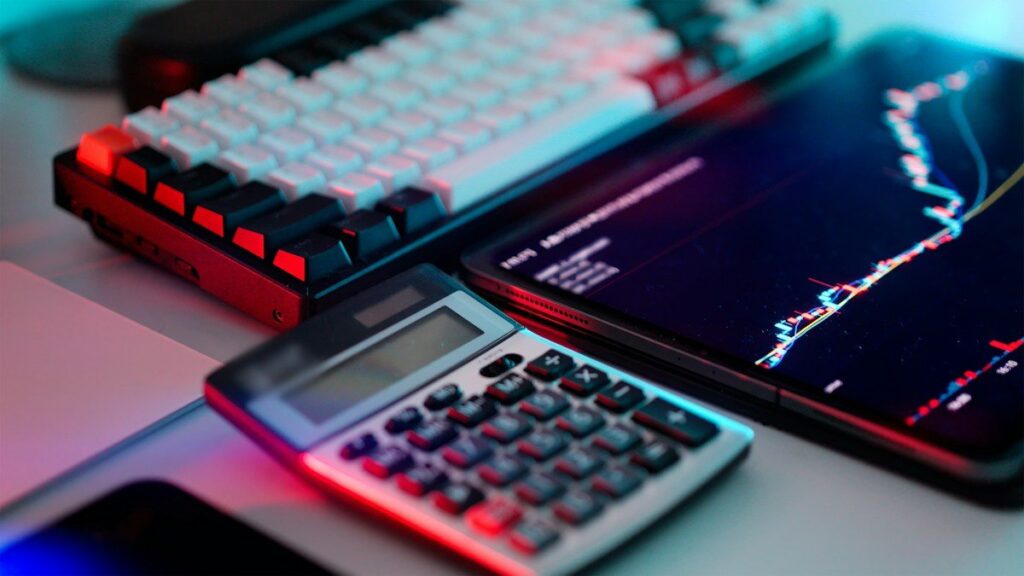 Trader using a calculator beside a notebook, working out position size for a thinner market
