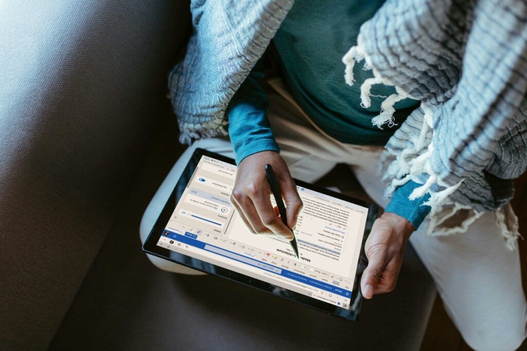 Person writing on a tablet showing a document