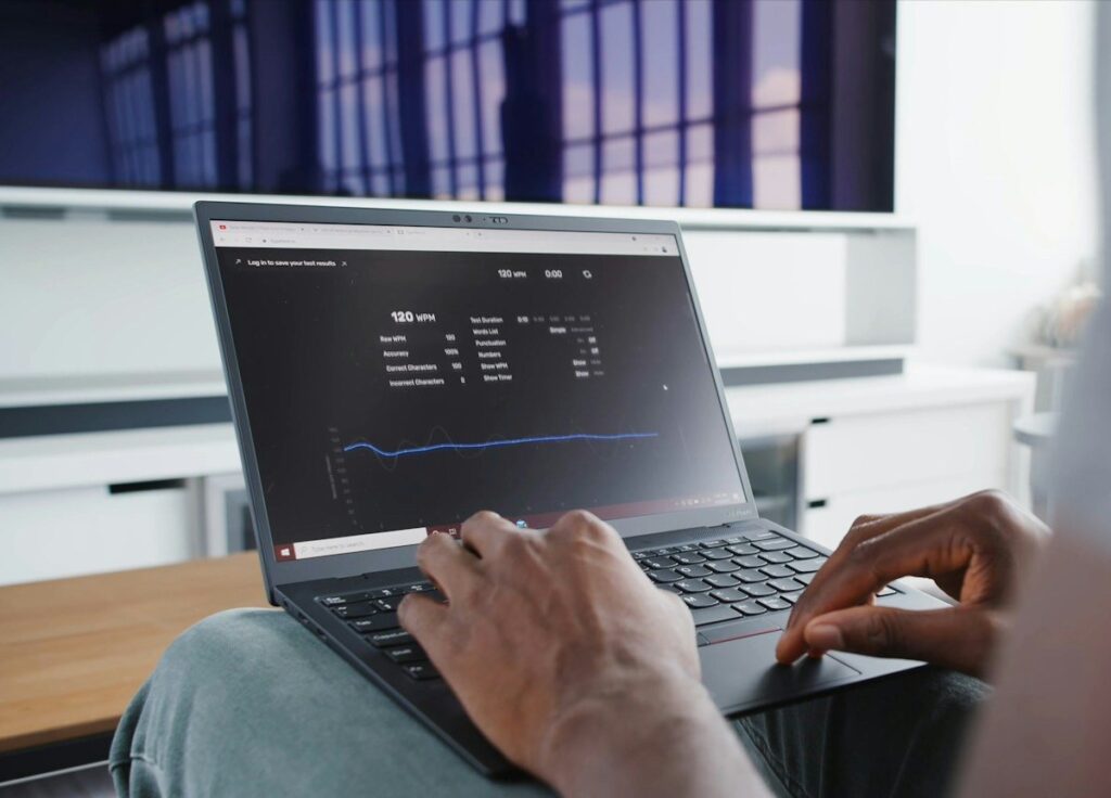 Person typing on a laptop showing a dashboard with a line chart
