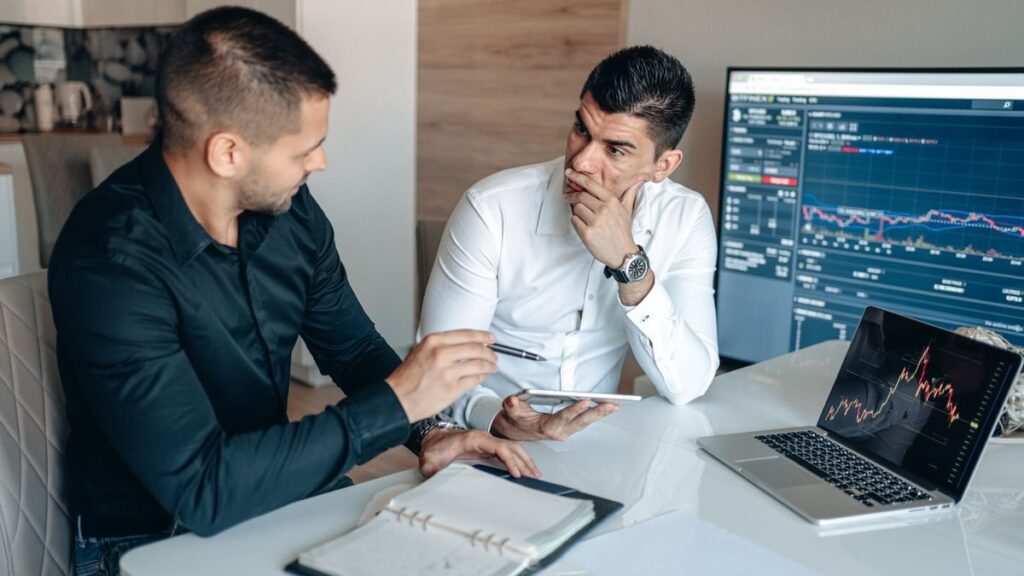 Traders discussing a chart on a large screen