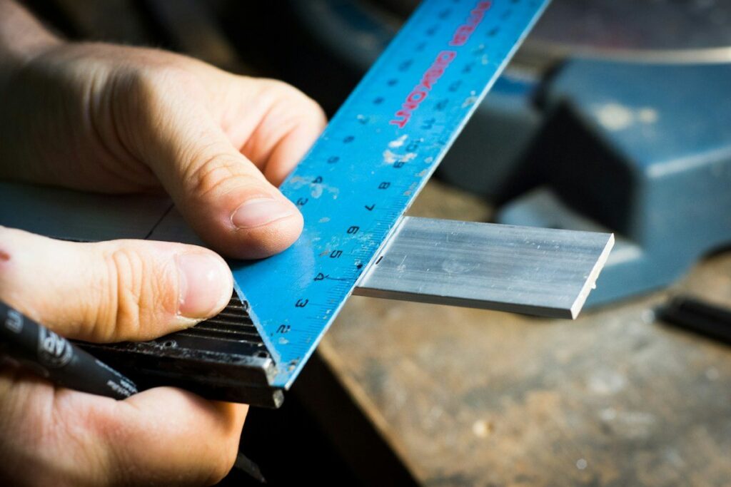 Hand measuring a printed sheet with a steel ruler, as when checking an inside bar stop distance against the target