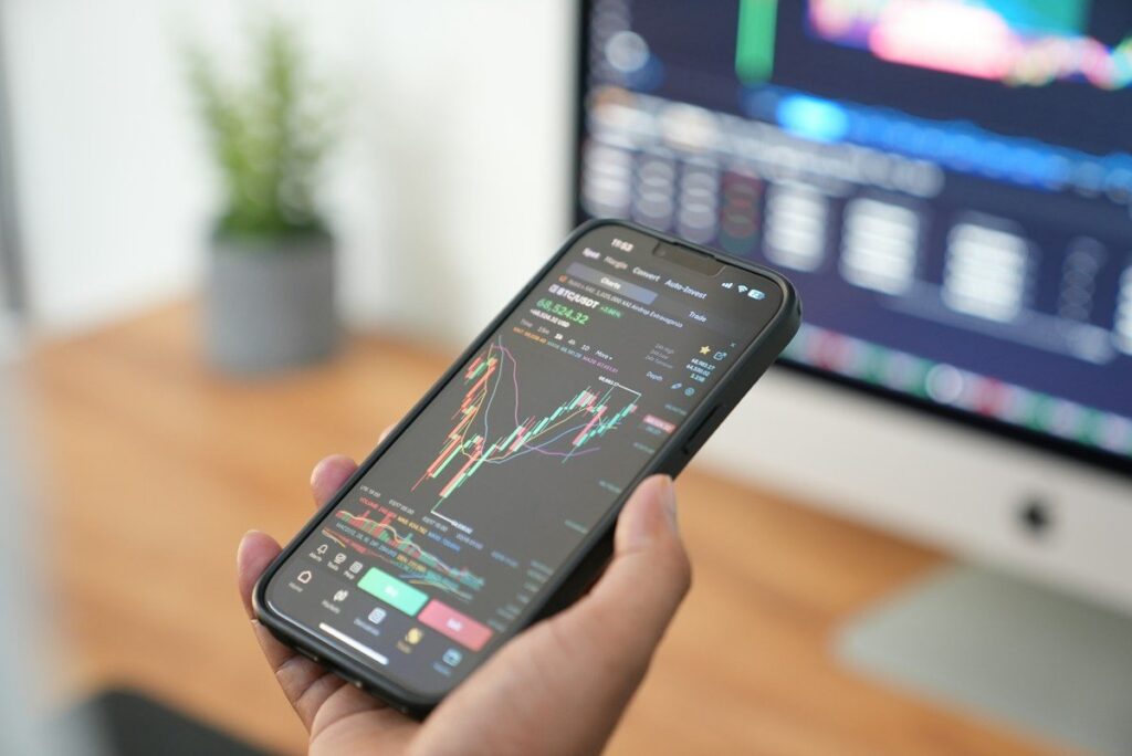 Trader checking a phone for opinions on an open position, looking for views that agree with the trade