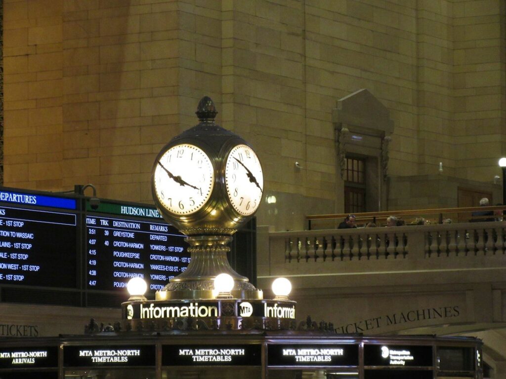 Station clock above departure boards in a grand hall