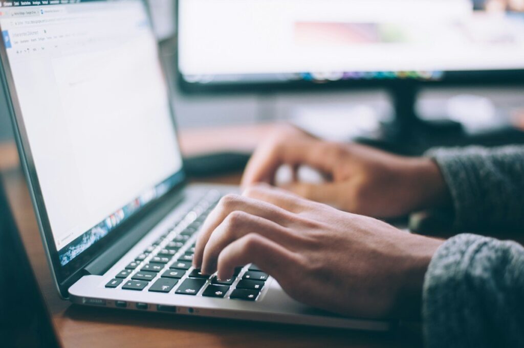 Trader typing on a laptop while checking stop distance before deciding how much to risk per trade