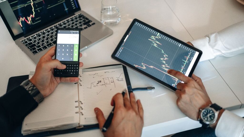 Hands with a phone calculator, notebook and tablet chart