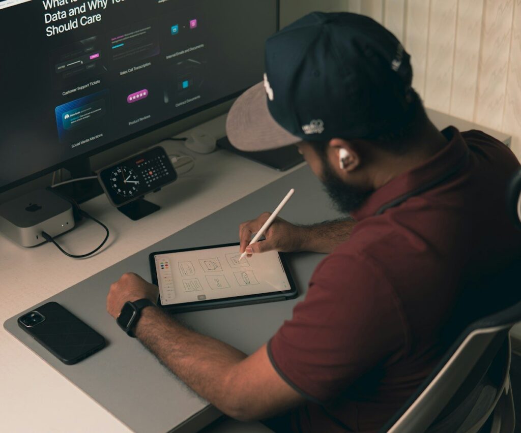 Man in a cap writing on a tablet at a desk