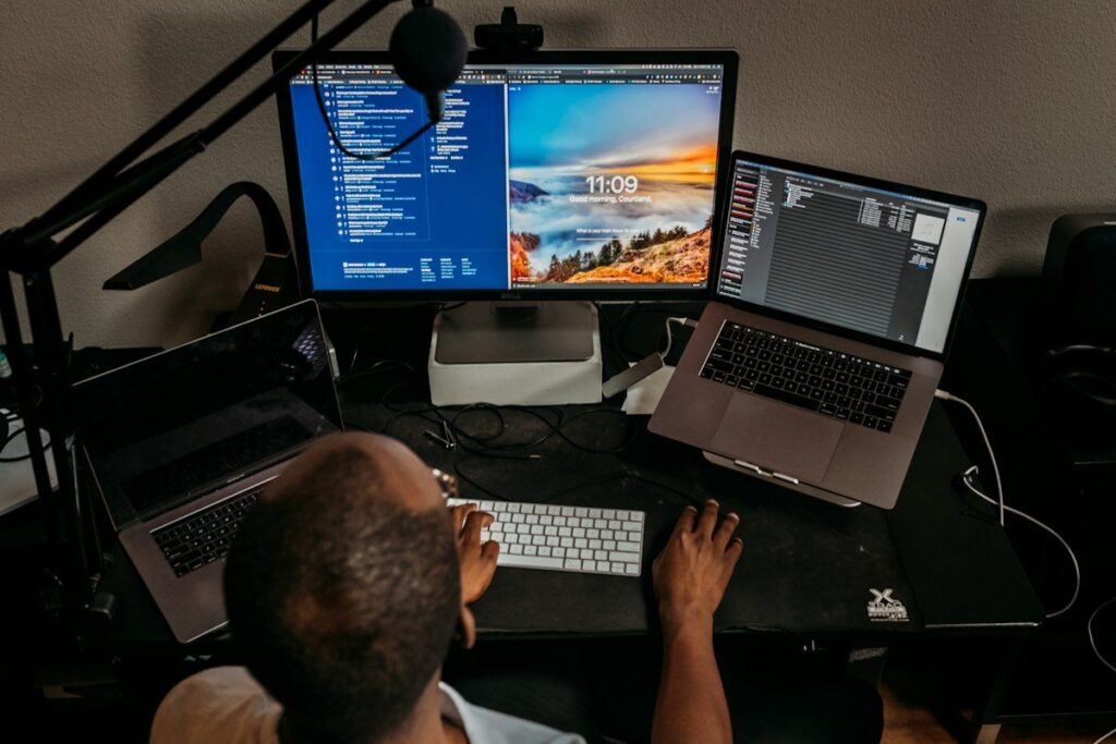 Trader at a desk with a large monitor and two laptops, comparing charts on separate screens
