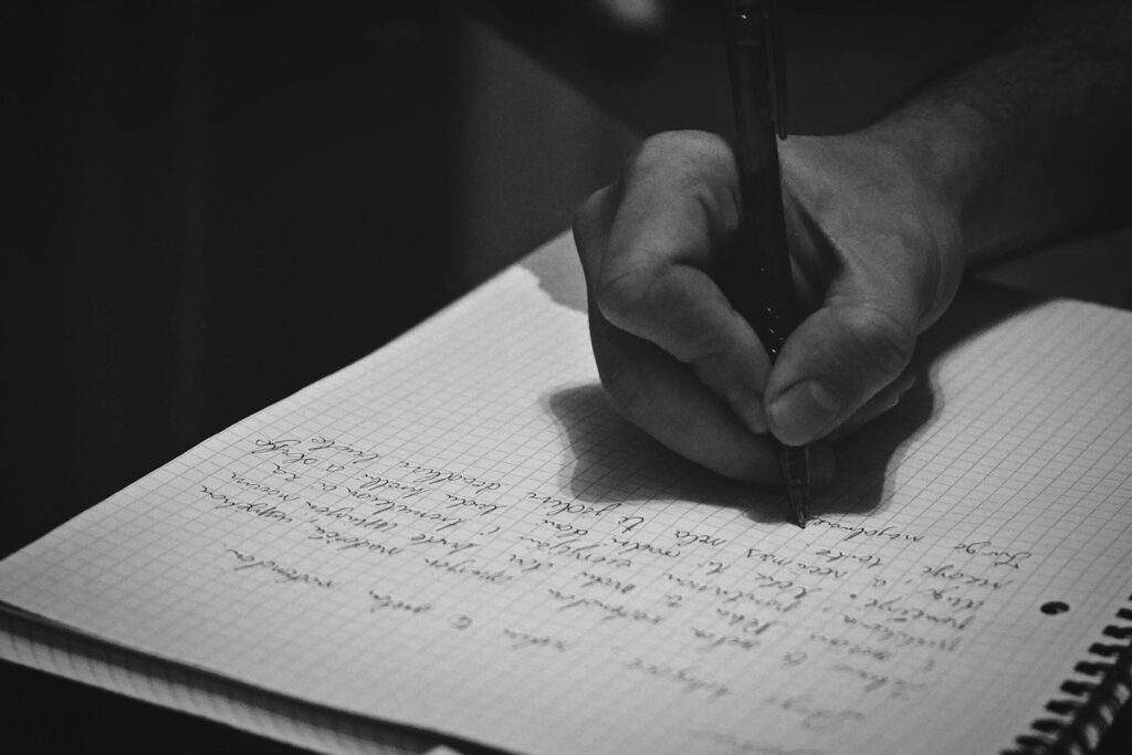 Hand writing tally marks in a notebook, counting the day's trades against a planned limit