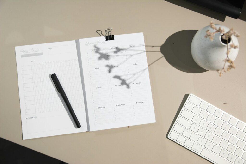 Printed planner sheets and a pen beside a keyboard on a desk