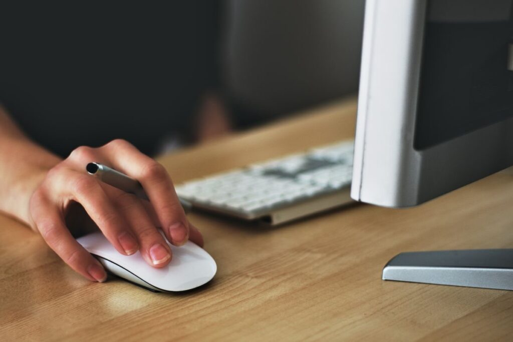 Hand on a computer mouse beside a monitor