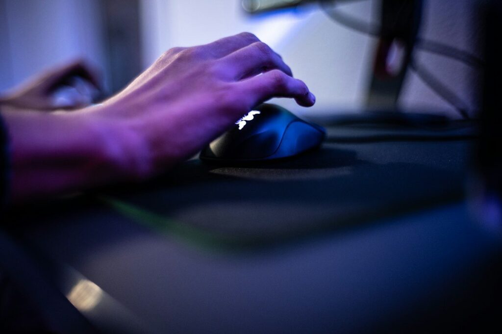 Hand on a mouse lit by purple light