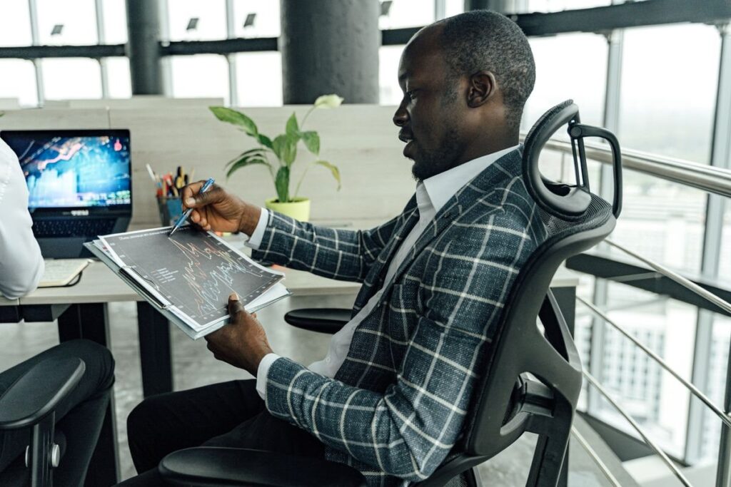 Man in a checked jacket holding a printed chart in an office