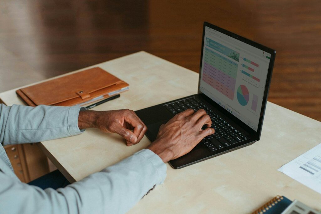 Person typing on a laptop showing charts and a table