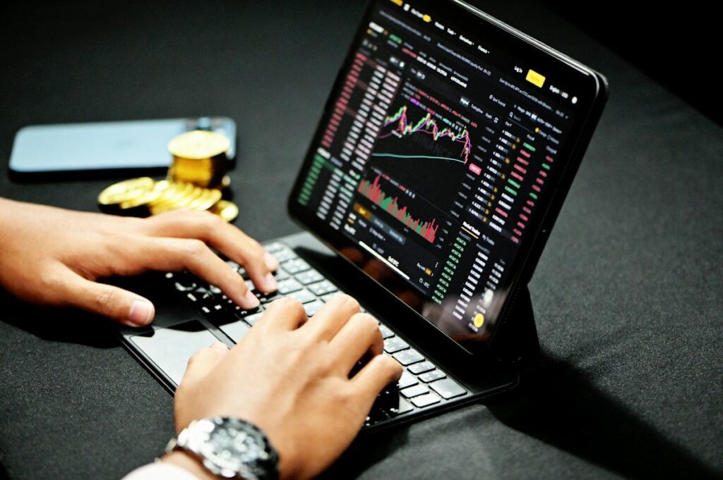 Hands typing on a tablet keyboard showing a trading platform