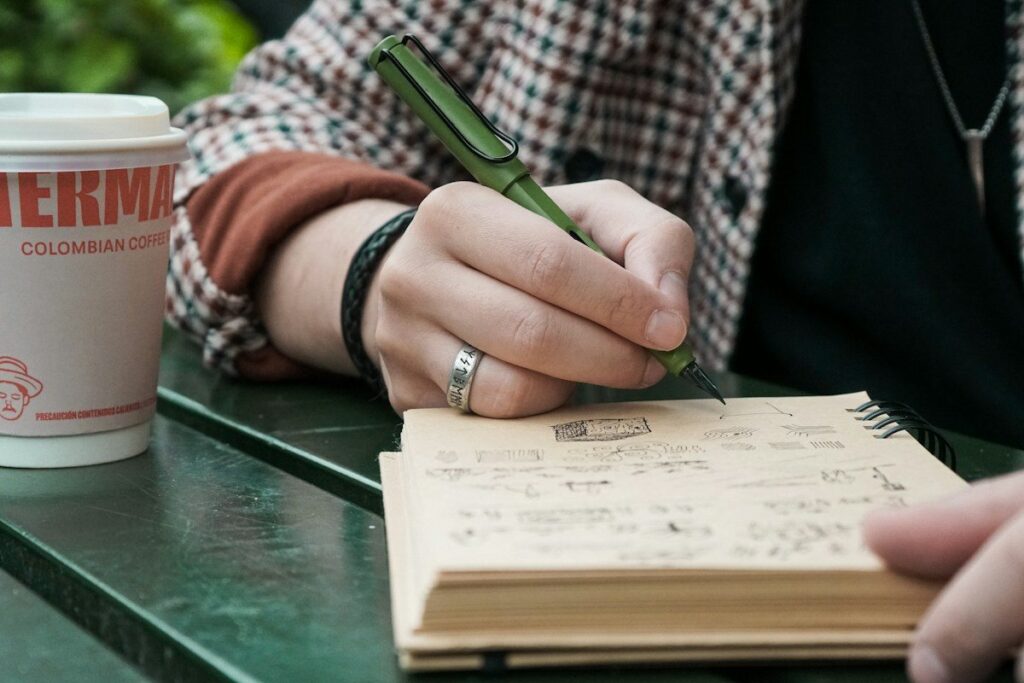 Person writing a hypothetical pin bar trade, its entry, stop and target, into a paper journal