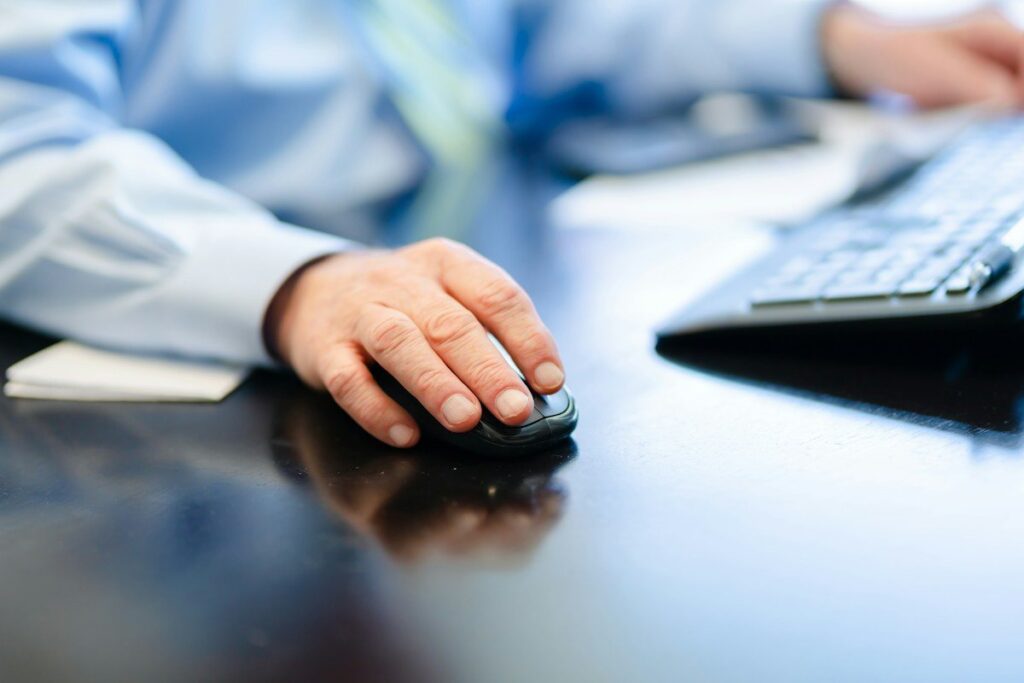 Hand on a mouse beside a keyboard