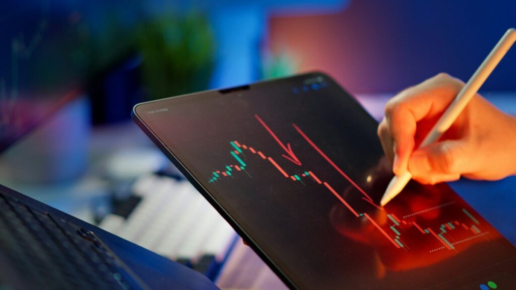 Trader drawing lines on a chart with a stylus on a tablet to compare price swings