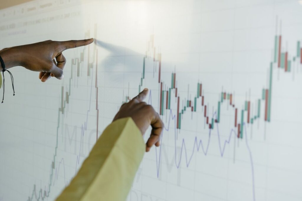Hands pointing at a candlestick chart on a white screen