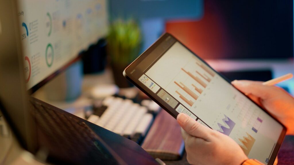 Hands holding a tablet showing bar charts