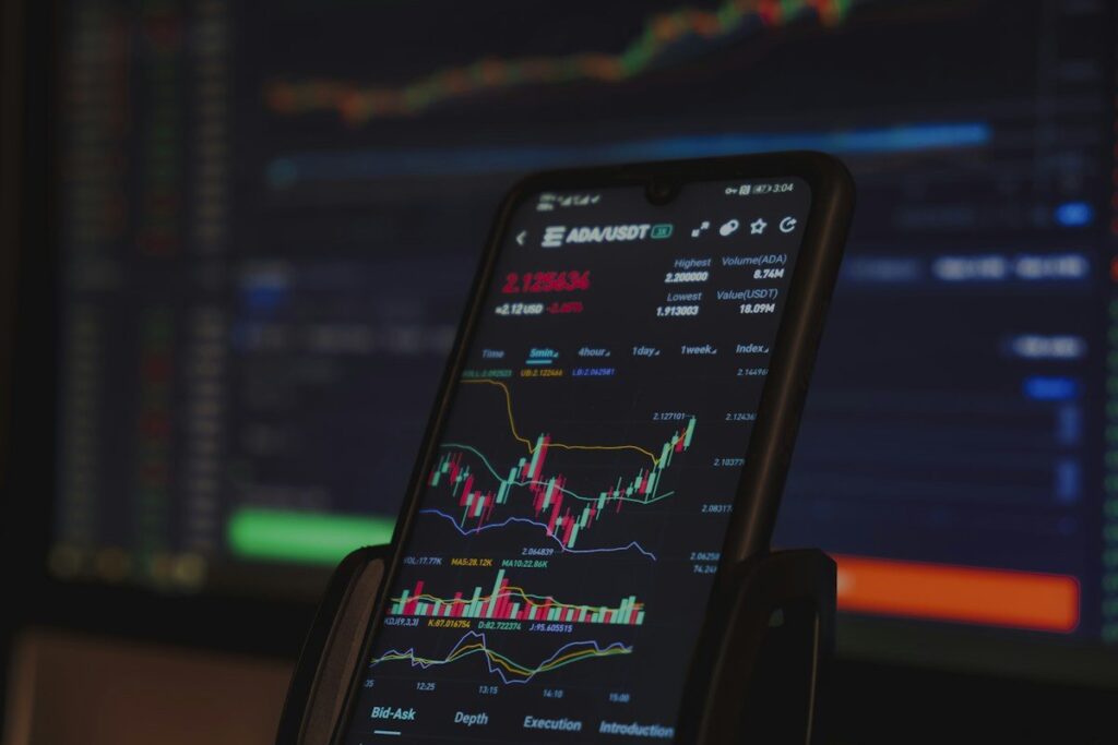 Phone on a stand showing a candlestick chart with indicators