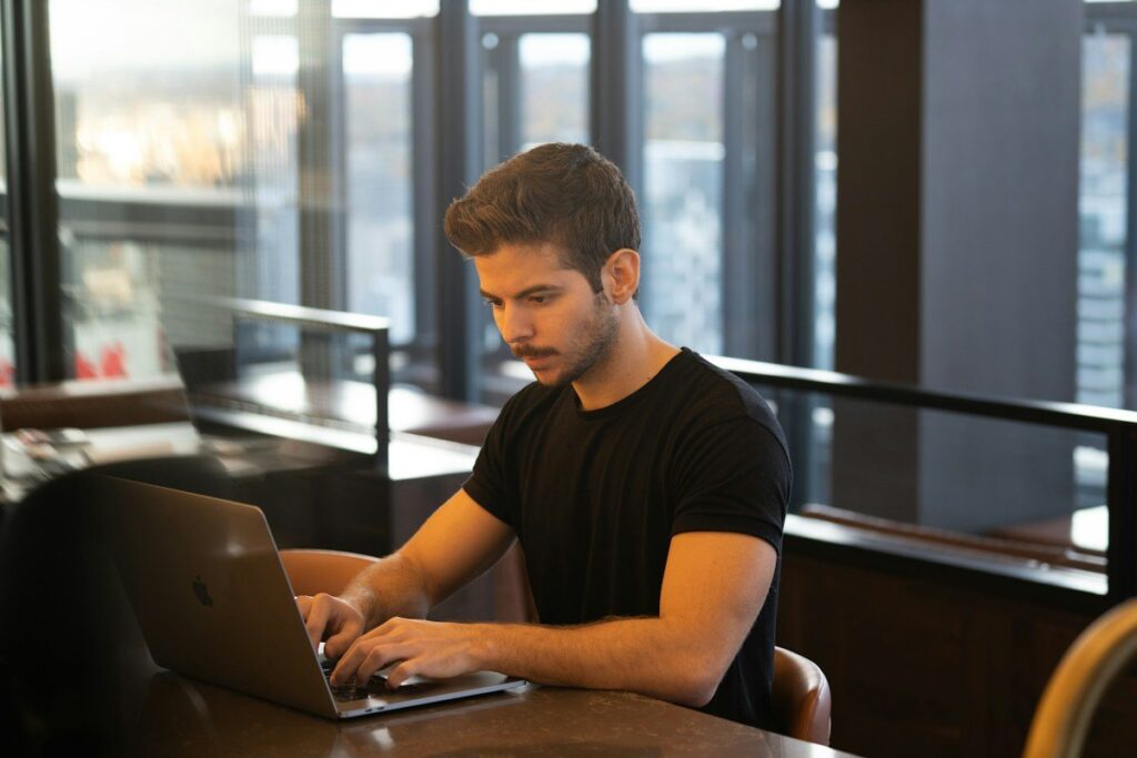 Trader hesitating over a laptop keyboard, noticing an impulse before placing an emotional trade