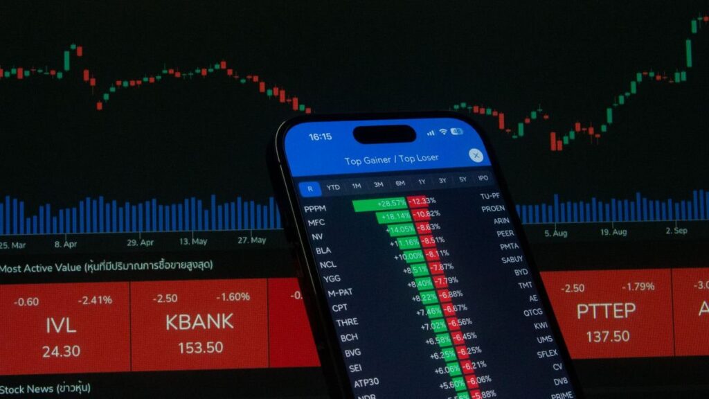 Phone showing a list of share prices in front of a chart