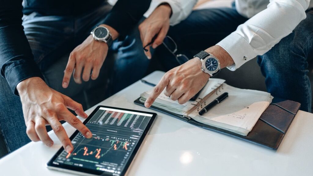 Hands pointing at a tablet chart beside a planner
