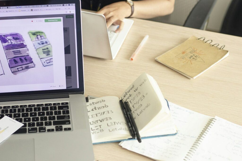 Notebook with handwritten notes beside a laptop on a desk