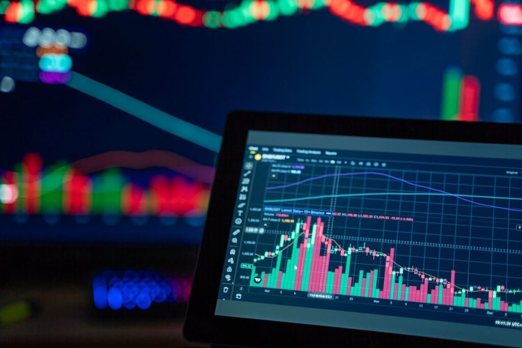 Tablet showing a candlestick chart in front of glowing screens