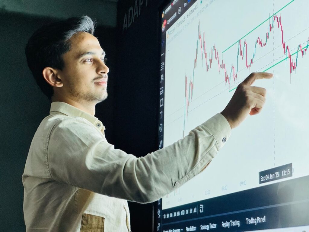 Man pointing at a line chart on a large screen