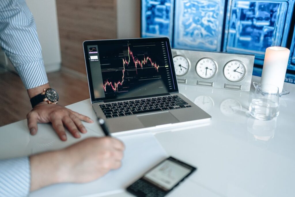 Hand writing beside a laptop showing a chart