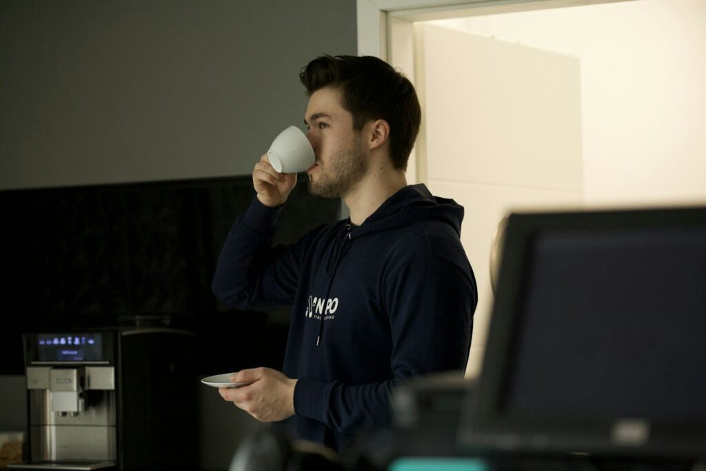 Man drinking coffee in an office near a monitor