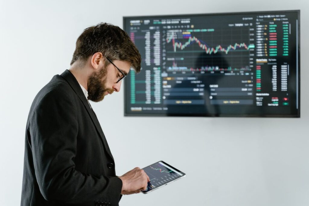 Man looking at a tablet in front of a wall screen of charts