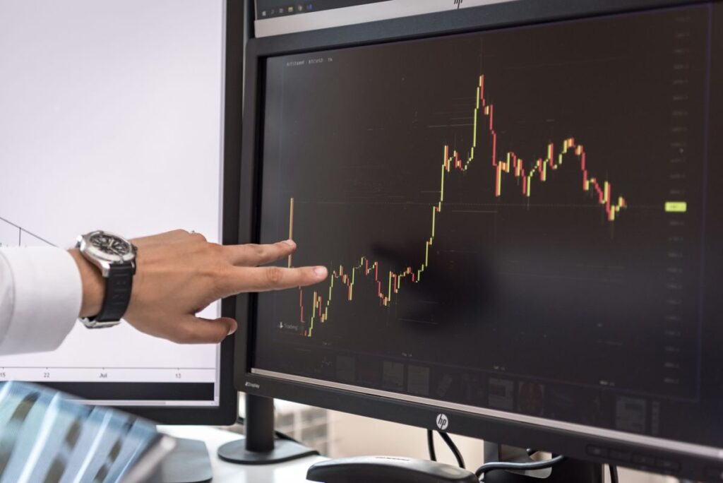 Hand pointing at a price chart on a monitor