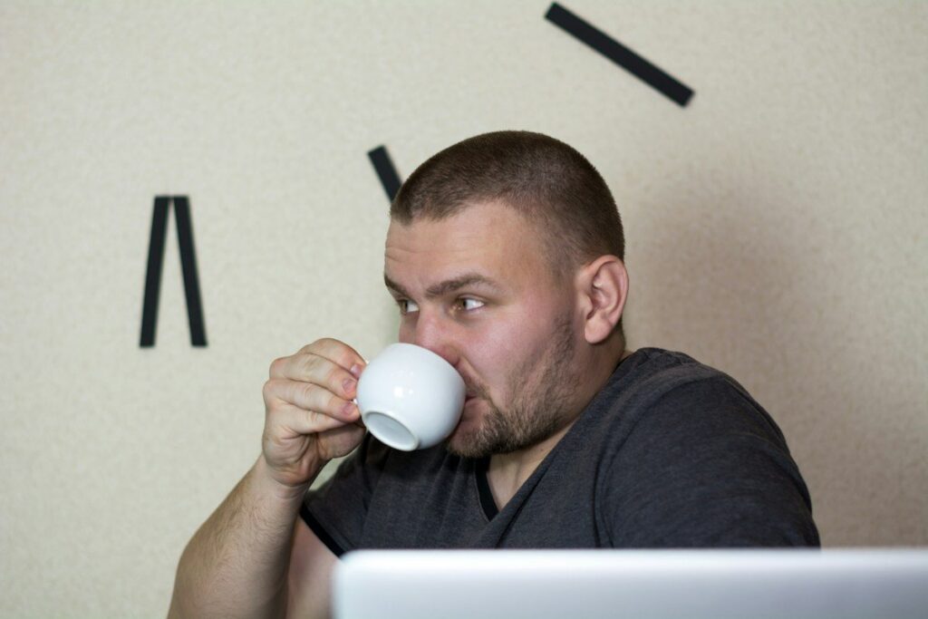 Man drinking from a cup at a desk