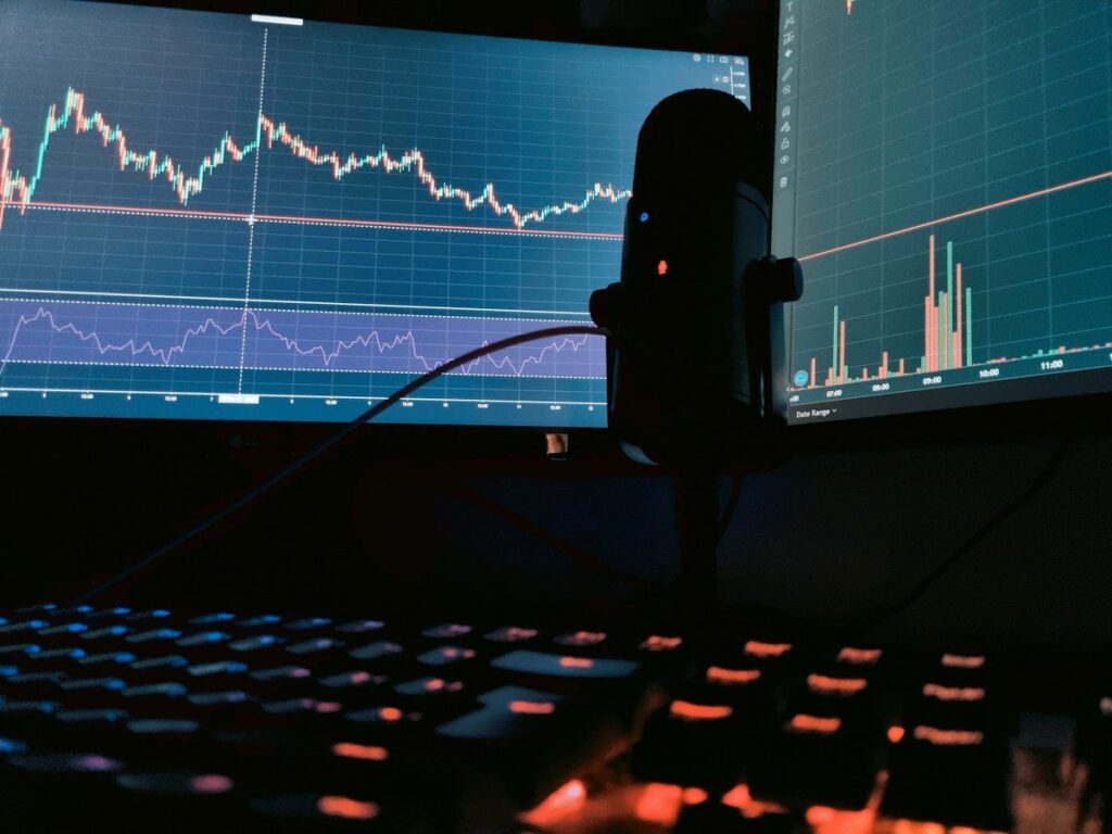 Trading charts on monitors behind a microphone