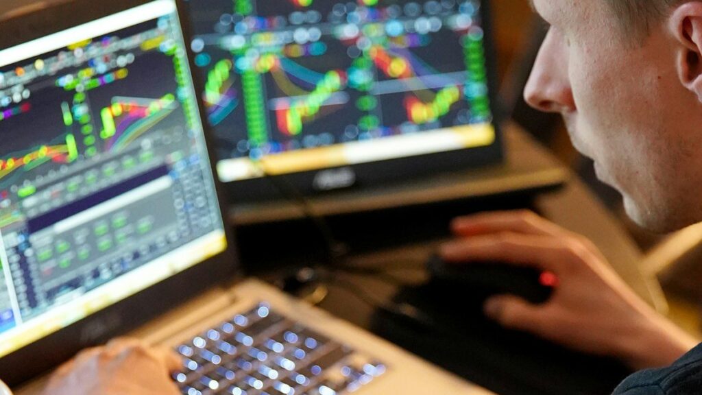 Trader leaning towards a monitor with a candlestick chart, watching momentum fade inside a wedge