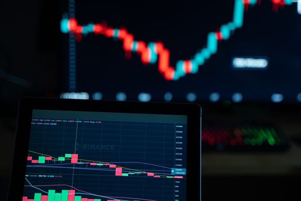 Candlestick chart on a monitor behind a laptop chart