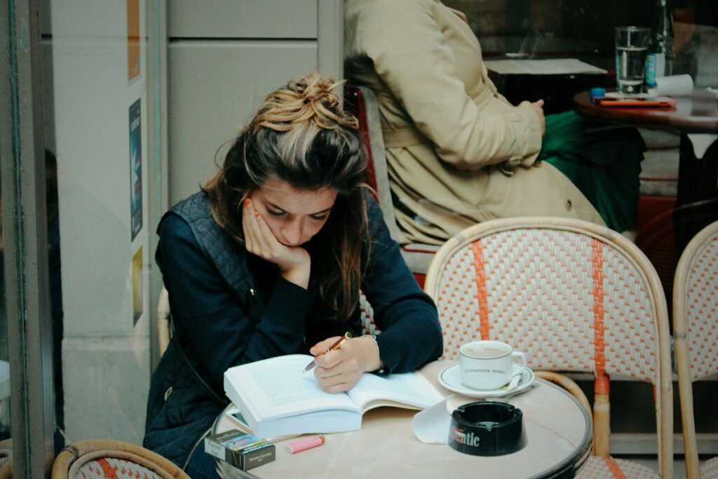 Person writing notes in a notebook at a cafe table, setting out a take-profit plan before entering a trade