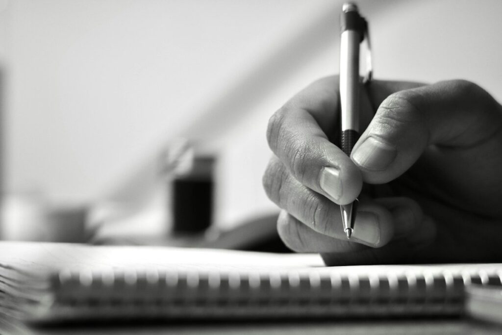Hand writing numbers in a spiral notebook, setting out the entry, stop and target for a bull flag trade
