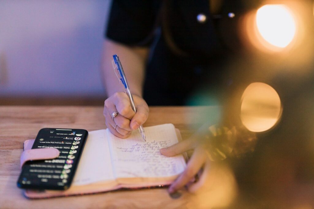 Person writing a checklist in a notebook, running a pre-trade liquidity check before placing an order