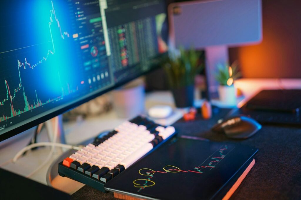 Desk with a keyboard and monitors showing charts