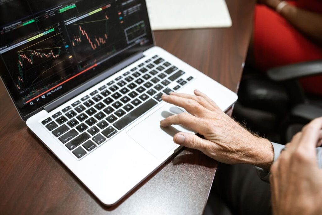 Hand on a laptop showing a price chart