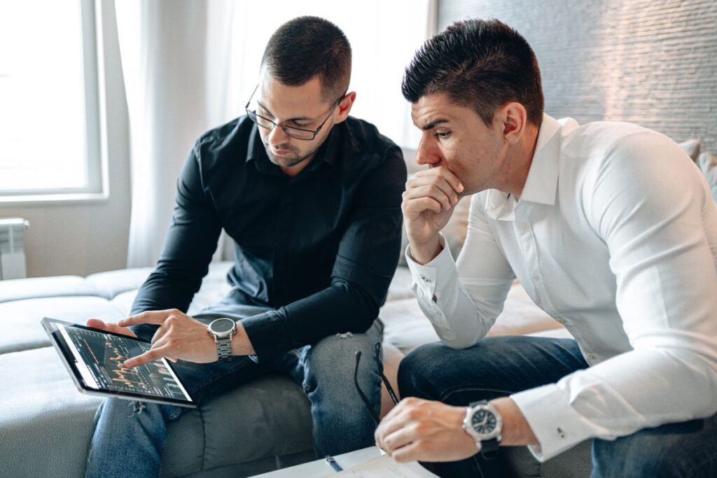 Two men in shirts studying a chart on a tablet