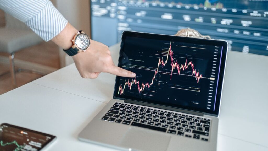 Hand pointing at a price chart on a laptop