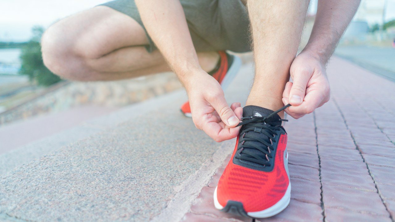 Runner tying the laces of a red trainer before a run, a picture of the daily routine behind trading discipline