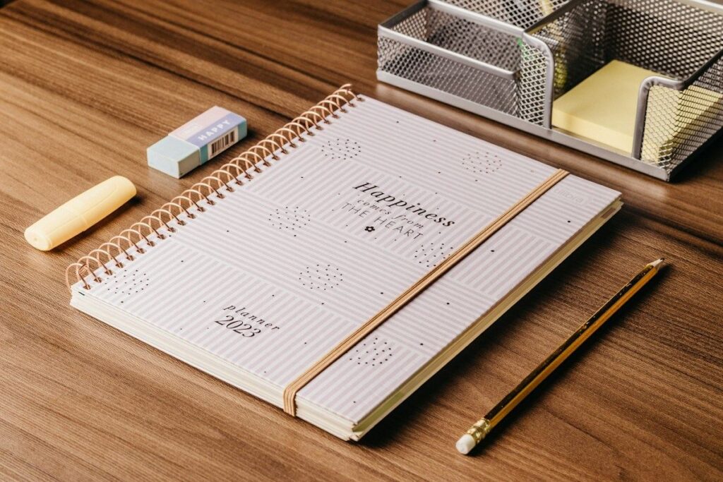 Spiral planner, pencil and eraser on a wooden desk